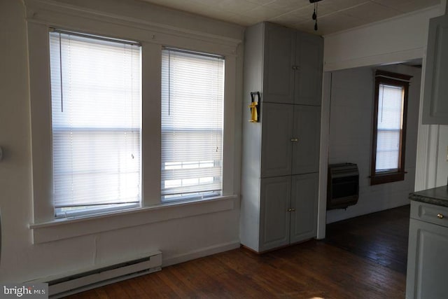 unfurnished room with dark wood-type flooring, heating unit, and a baseboard radiator