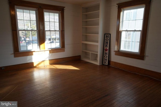 spare room with built in shelves, baseboards, and dark wood-style flooring