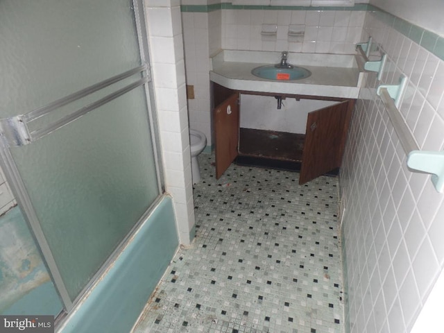 bathroom with vanity, shower / bath combination with glass door, tile patterned flooring, tile walls, and toilet