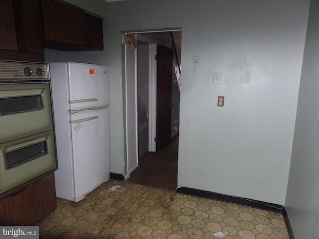 kitchen featuring tile patterned floors, multiple ovens, freestanding refrigerator, and baseboards