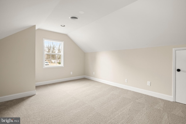 additional living space featuring lofted ceiling, light colored carpet, visible vents, and baseboards