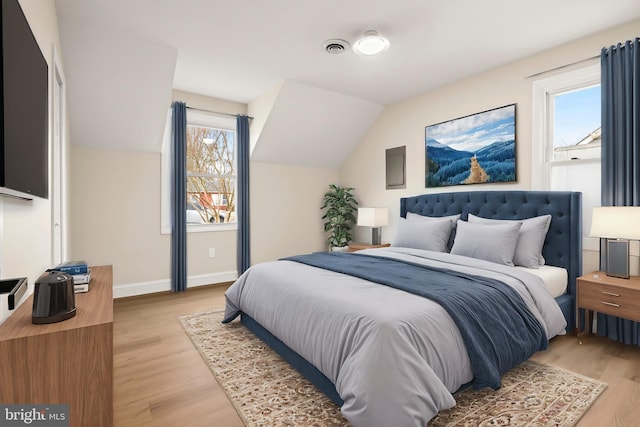 bedroom featuring baseboards, lofted ceiling, light wood-style floors, and visible vents