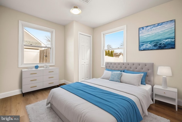 bedroom with baseboards, multiple windows, and wood finished floors