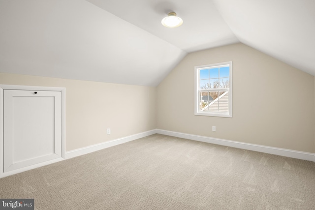 additional living space with light colored carpet, baseboards, and vaulted ceiling