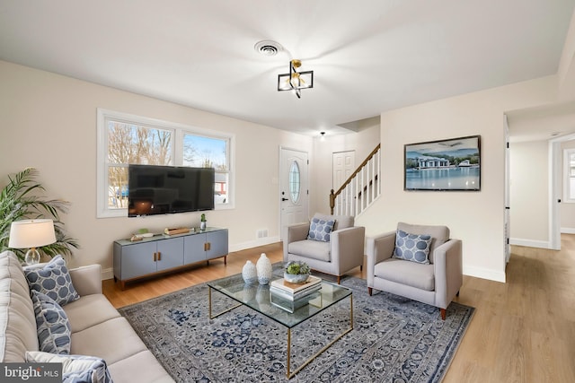 living room featuring visible vents, baseboards, and wood finished floors