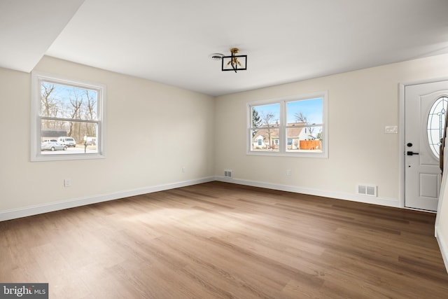 entrance foyer featuring visible vents, a healthy amount of sunlight, and wood finished floors