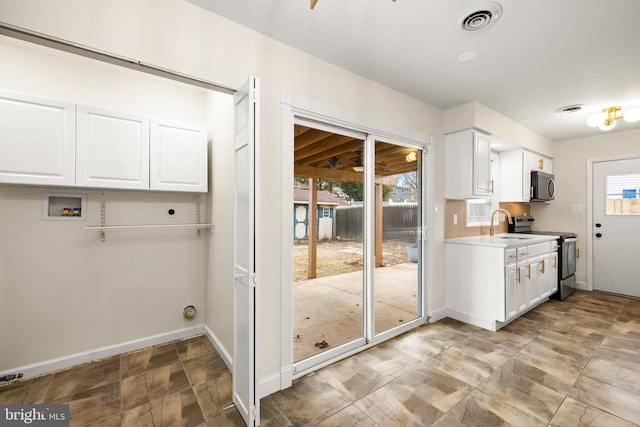 kitchen with visible vents, stainless steel appliances, white cabinets, light countertops, and baseboards