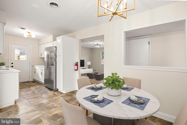 dining space with a notable chandelier, visible vents, and baseboards