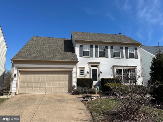 colonial-style house featuring concrete driveway, an attached garage, and a shingled roof