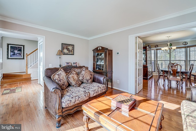 living room featuring hardwood / wood-style floors, baseboards, ornamental molding, stairs, and a chandelier