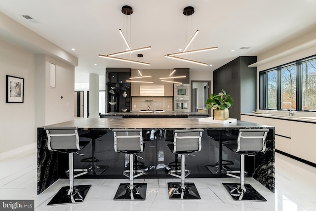 kitchen with visible vents, a large island, modern cabinets, white cabinets, and decorative backsplash