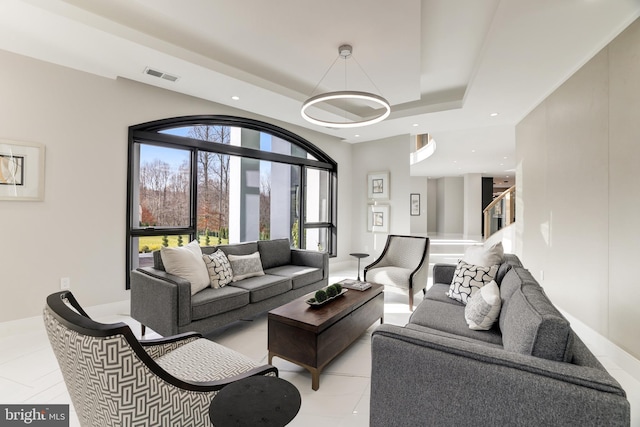 living room with visible vents, recessed lighting, baseboards, stairway, and a raised ceiling