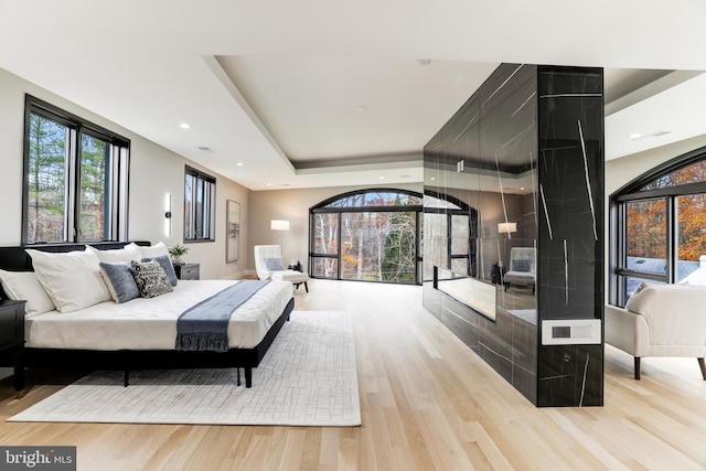 bedroom with a raised ceiling, recessed lighting, and wood finished floors