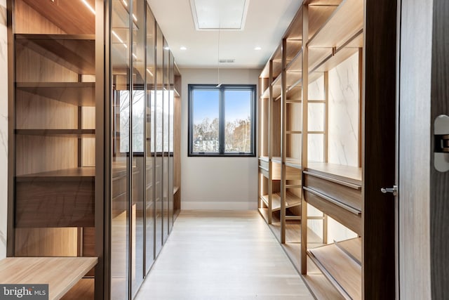 walk in closet featuring attic access, light wood-style flooring, and visible vents