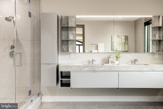 full bathroom featuring double vanity, a stall shower, tile patterned floors, and a sink