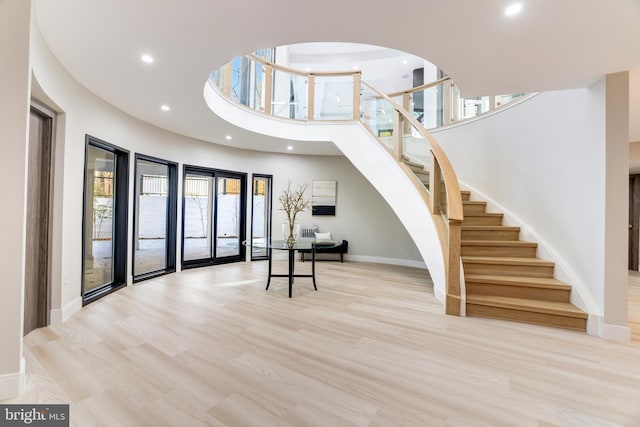 foyer with a high ceiling, recessed lighting, wood finished floors, and baseboards