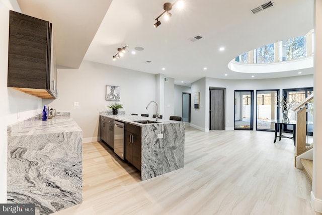 kitchen featuring visible vents, light wood-style flooring, a sink, baseboards, and dishwasher