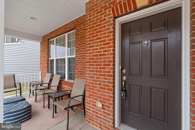 property entrance featuring brick siding and a porch