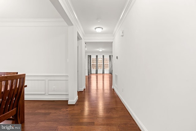 corridor featuring dark wood finished floors, visible vents, a decorative wall, and crown molding