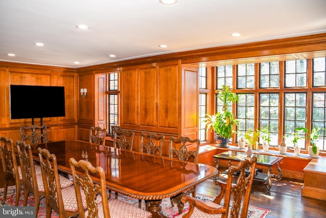 dining area with dark wood finished floors, recessed lighting, crown molding, and wood walls