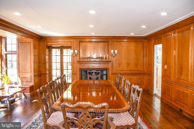 dining space with crown molding, a decorative wall, a fireplace, and dark wood-style flooring