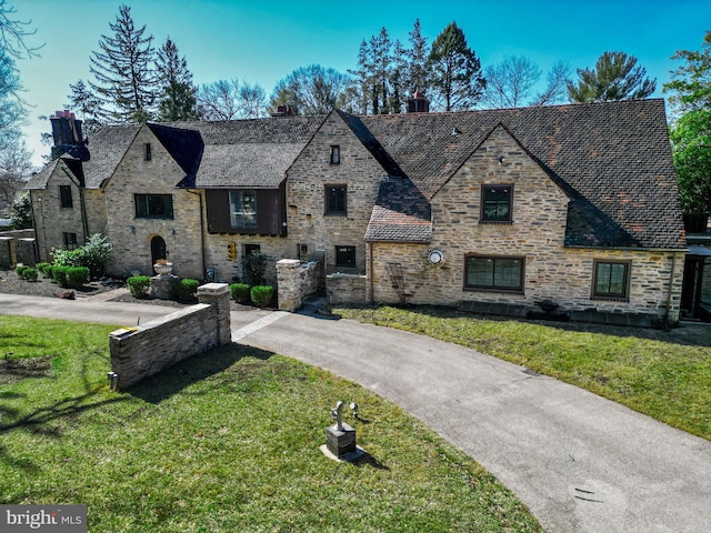 view of front of home with a front lawn, stone siding, and driveway