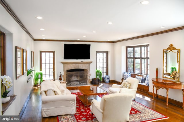 living area featuring baseboards, a tiled fireplace, ornamental molding, recessed lighting, and wood finished floors