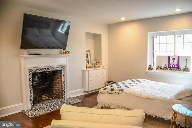 bedroom with recessed lighting, wood finished floors, baseboards, and a tile fireplace