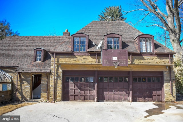 french country home with driveway, a high end roof, stone siding, a garage, and a chimney