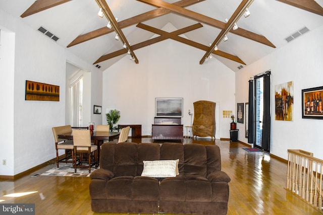 living area featuring hardwood / wood-style flooring, rail lighting, visible vents, and beam ceiling