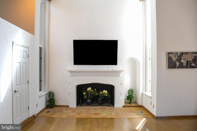 unfurnished living room with a fireplace with flush hearth, wood finished floors, visible vents, and baseboards