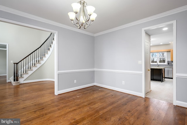 unfurnished room featuring crown molding, an inviting chandelier, hardwood / wood-style floors, stairs, and baseboards