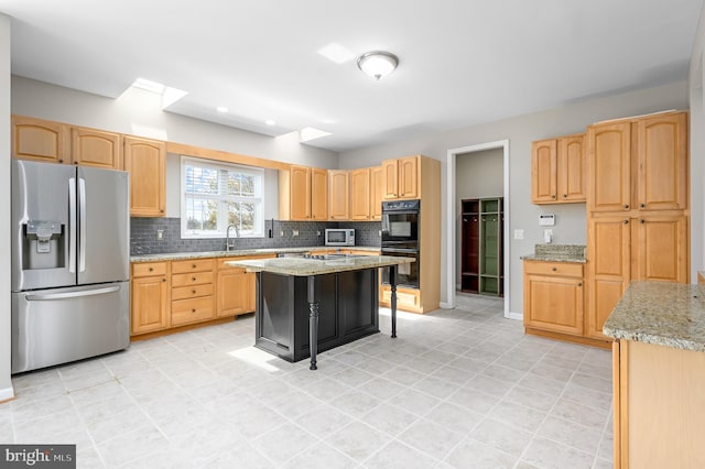 kitchen with backsplash, a sink, appliances with stainless steel finishes, and light brown cabinetry