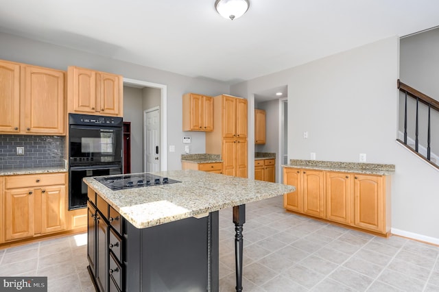 kitchen featuring light brown cabinetry, a breakfast bar, decorative backsplash, light tile patterned floors, and black appliances