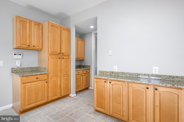 kitchen featuring light stone counters, light brown cabinets, recessed lighting, baseboards, and light tile patterned floors