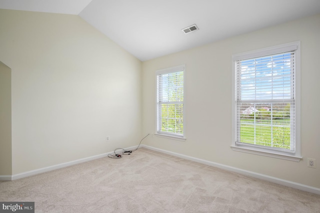 carpeted spare room featuring baseboards, visible vents, a healthy amount of sunlight, and lofted ceiling