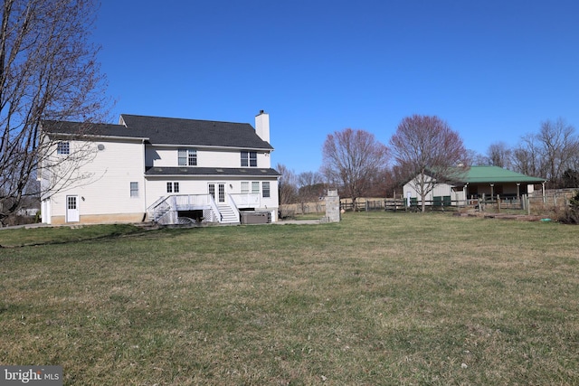 rear view of property with stairs, a lawn, fence, and a chimney