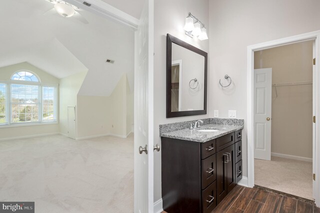 bathroom featuring vanity, baseboards, a ceiling fan, and vaulted ceiling