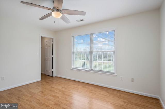 empty room featuring baseboards, a ceiling fan, light wood-style flooring, and visible vents
