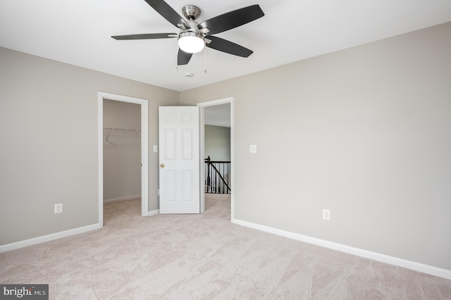 unfurnished bedroom featuring baseboards, carpet flooring, a spacious closet, and a closet