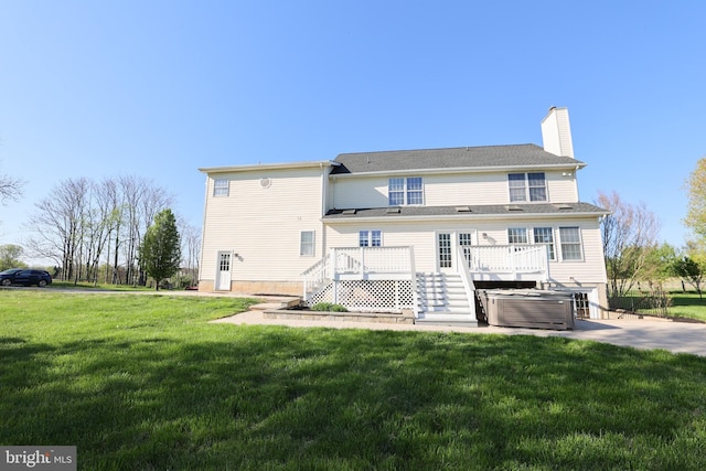 rear view of property featuring a hot tub, a deck, a yard, and stairway