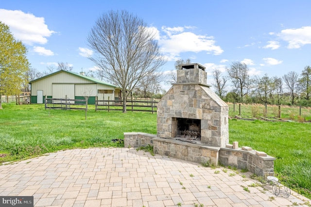 view of patio featuring an outdoor stone fireplace, fence, and a pole building