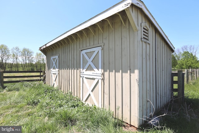 view of outdoor structure with fence and an outbuilding