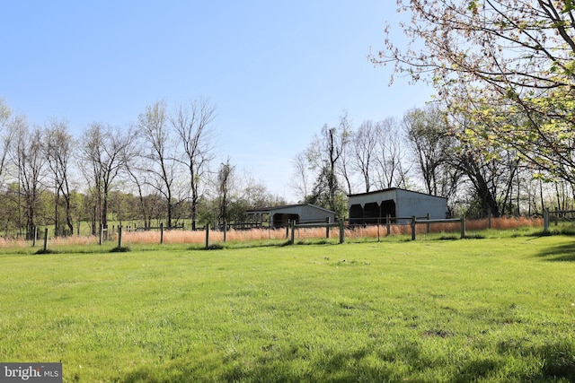 view of yard featuring a pole building, a rural view, fence, and an outbuilding