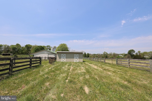 view of yard with an outdoor structure, fence, and a rural view