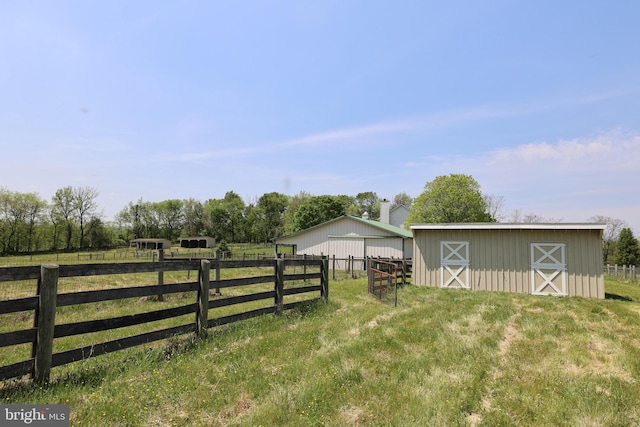view of yard featuring a barn, an exterior structure, fence, and an outbuilding