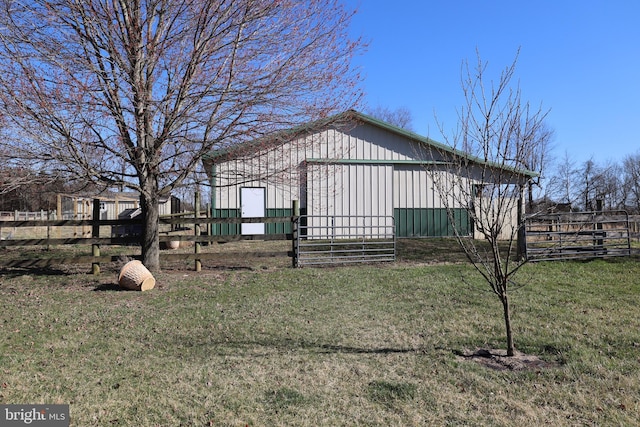 exterior space with fence, an outbuilding, board and batten siding, and a yard