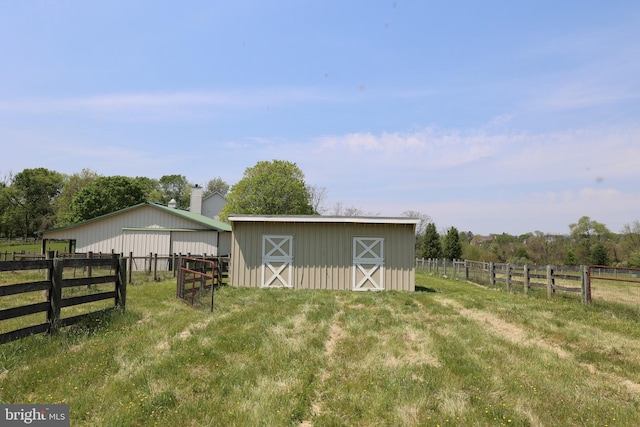 view of barn with an exterior structure, fence, and a yard