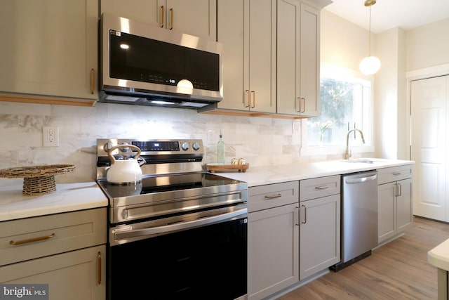 kitchen featuring tasteful backsplash, light wood finished floors, appliances with stainless steel finishes, and a sink