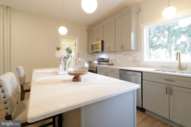 kitchen with tasteful backsplash, gray cabinetry, a center island, stainless steel appliances, and a sink